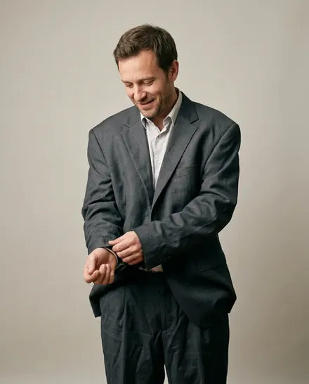 Un homme dans un costume du commerce trop grand : les manches lui couvrent les mains